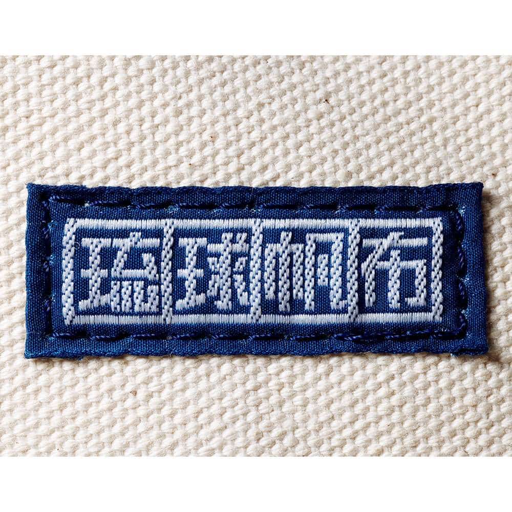 国産帆布だけを使用し、八重瀬町にある自社工場で型取り・裁断・縫製から検品までを一貫して行なう琉球帆布。この織ネームはその製品だけに付けられる。