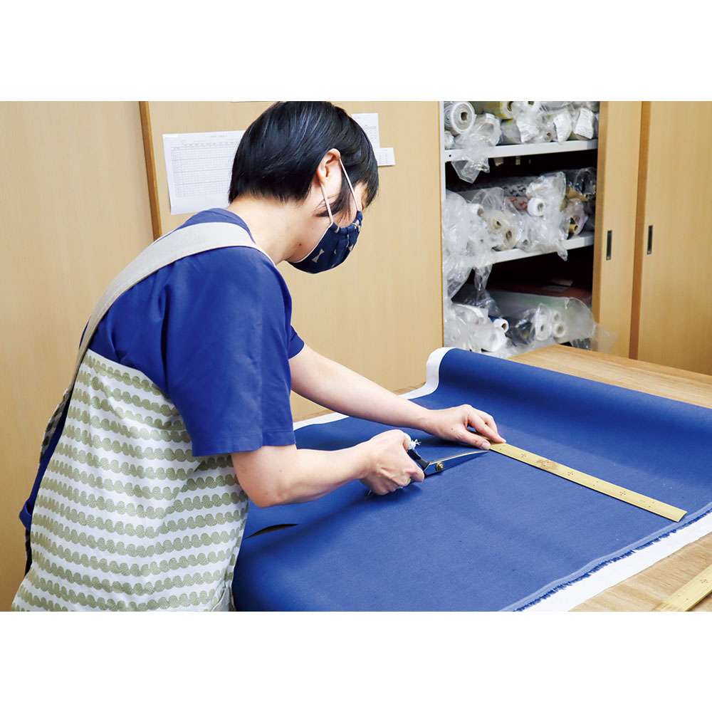 麻の中でも繊維が細くしなやかなリネンの生地を裁断。熟練職人により素早く正確に作業が進められる。