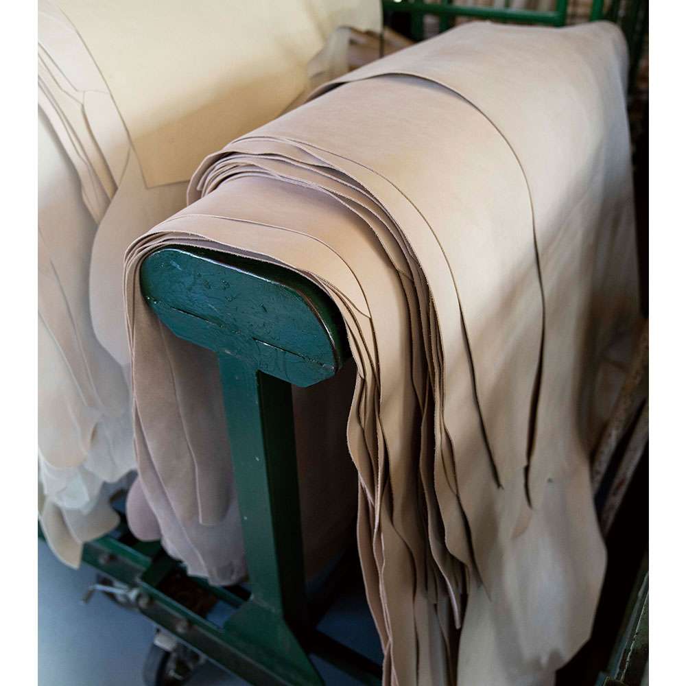 バングラディシュから仕入れた植物タンニンでなめされたヌメ革（写真）に、何度も色調整をしたのち、インクジェットプリンターで印刷する。